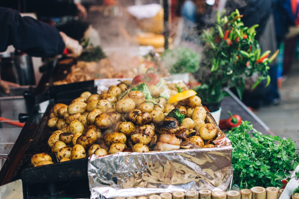 Roasted whole potatoes with vegetables at a food market