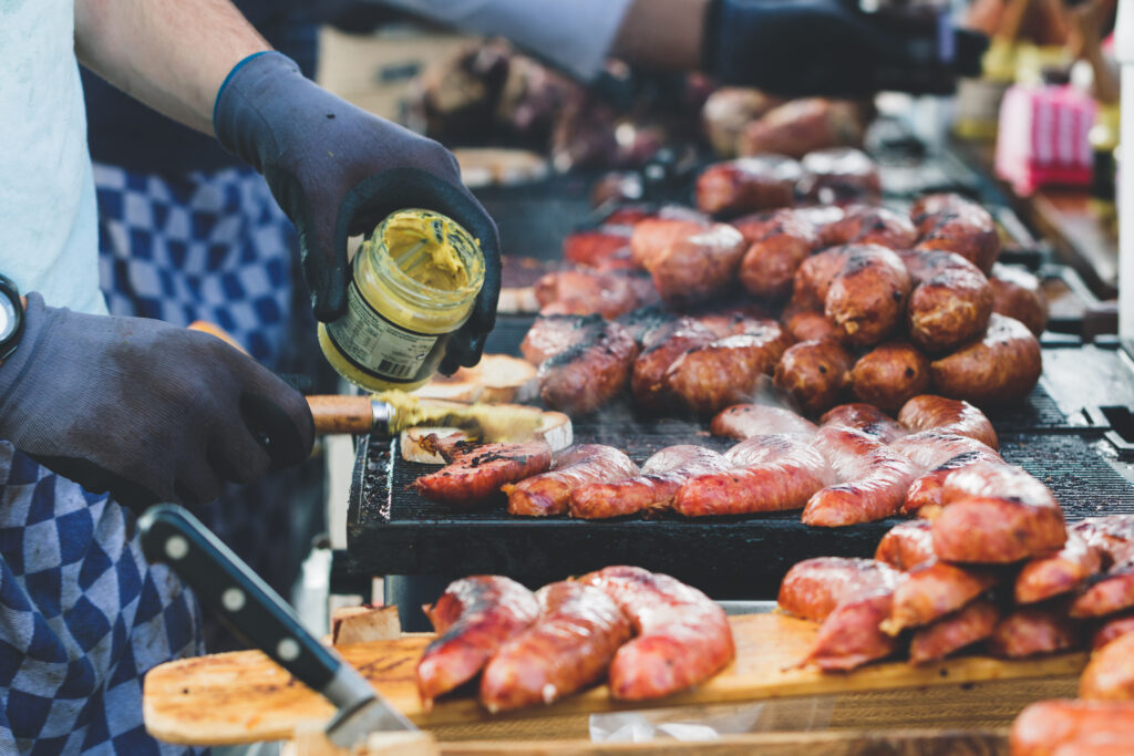 Street food in Amsterdam on sunday market. Toasts with fried sausages and mustard.